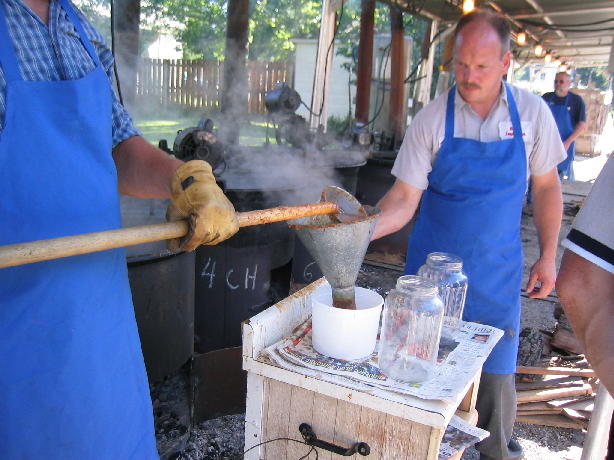 John Sheehan holds a funnel while hot burgoo is ladled into a container for kettle service.