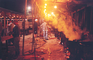 Steam from kettles of boiling burgoo rises in the night