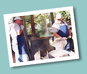 Tony Thomas and Roger Witte remove hot embers from the firebox under one of the kettles.