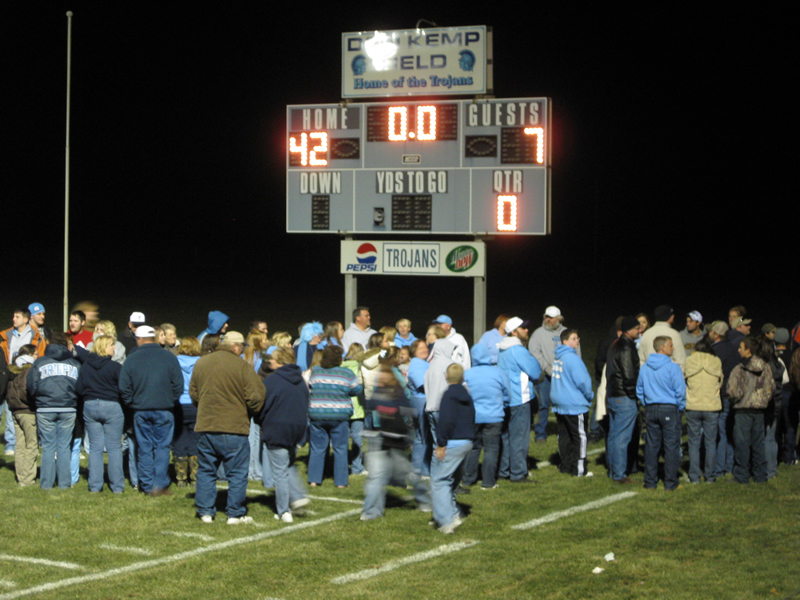 A few hundred fans celebrate the team's return to Don Kemp Field. The final score of the championship game is shown on the scoreboard.