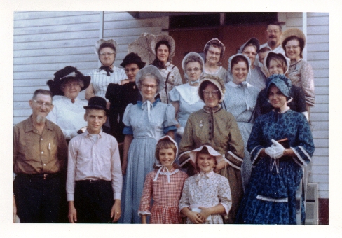 Celebrating Arenzville's Sesquicentennial in 1964: Front row, left to right: Leo Jones, Tony Clark, Martha Clark, Molly Clark, Ann Dober (in blue dress). 2nd row: Lucy Shannon, Mildred Kolberer, Elsie Kolberer. 3rd row: Virginia Busen (in black dress), Myrtle Zillion, Linda Busen, Sara Clark (partially hidden behind Ann Dober). Back row: Wilma Jones, Fran Hobrock (with parasol), Olga Dober, Loretta Jones (partially hidden), young boy (Tom Busen?), Bert Kolberer, and Roberta Clark.